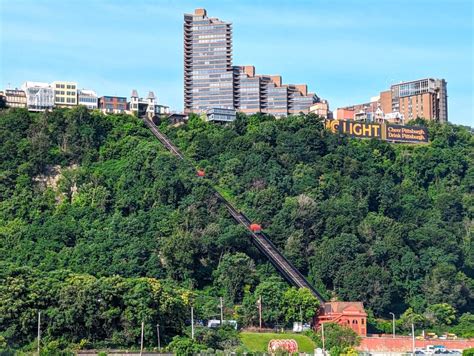 The incline track climbing the wooded hillside of Mount Washington in Pittsburgh with apartment towers on the ridge