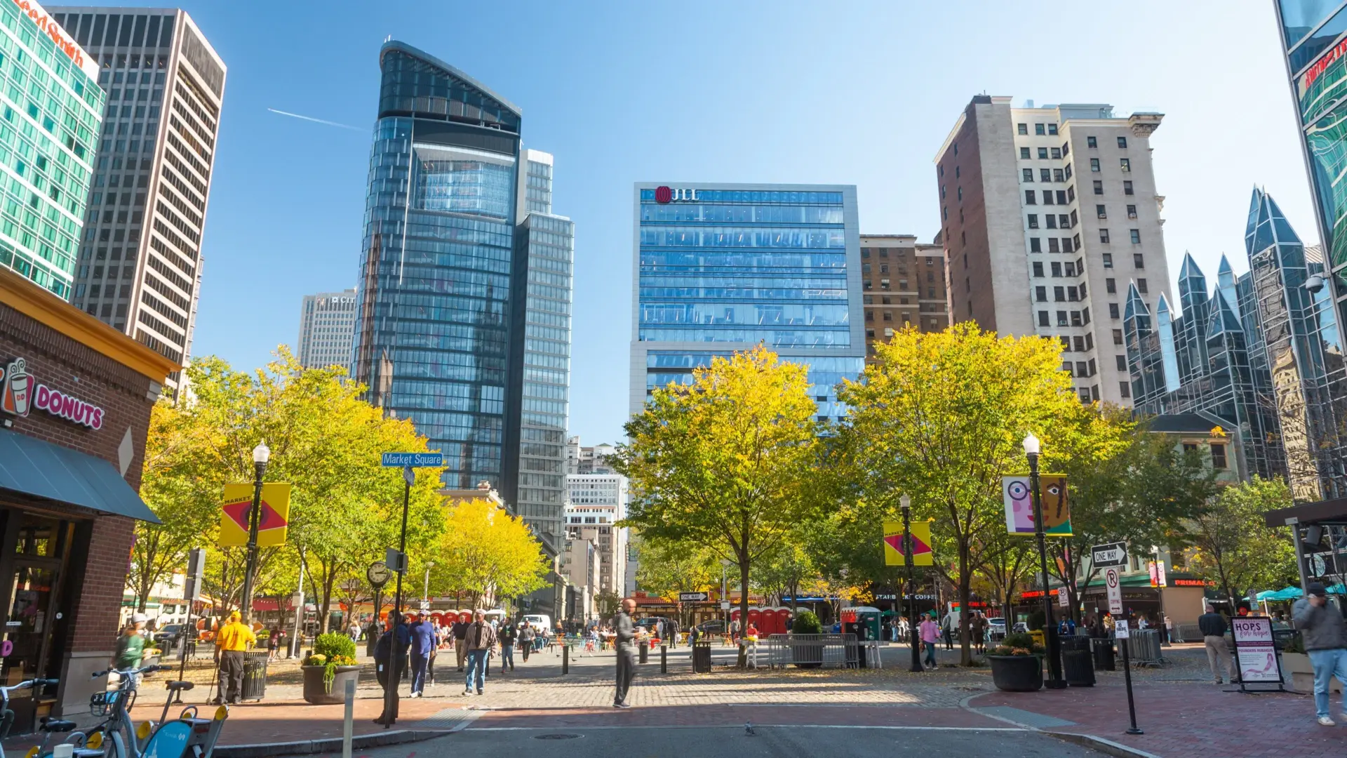 Market Square in Downtown Pittsburgh on a sunny autumn day with people, trees and the skyline behind