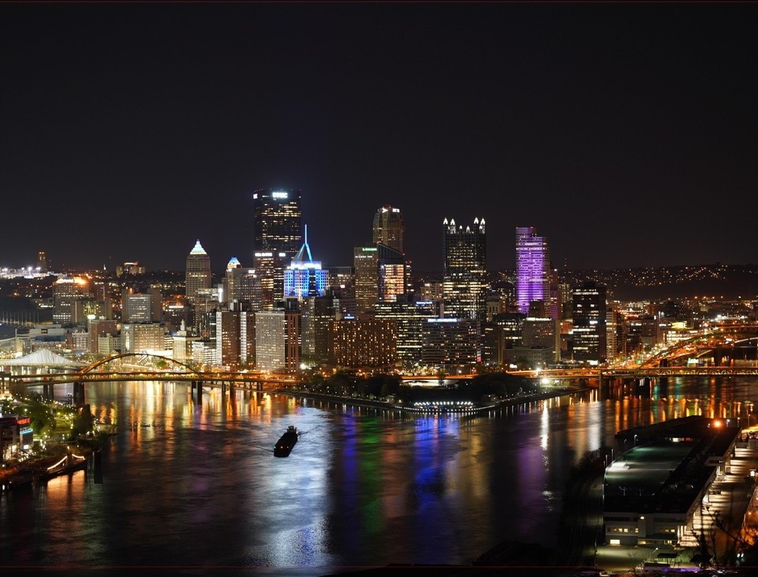 Pittsburgh's downtown skyline at night reflected in the river — the canvas hanging above the living room couch